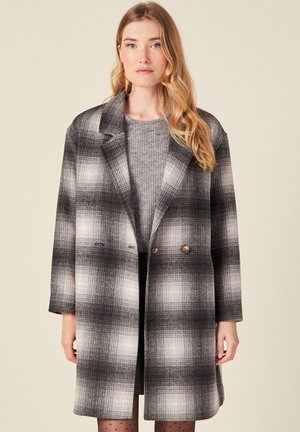 Cappotto doppiopetto in un motivo a quadretti bianco e nero, realizzato in tessuto texturizzato con colletto strutturato e tasche frontali.