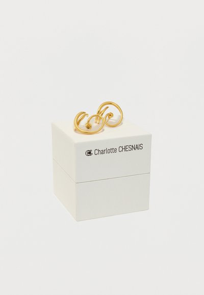Χρυσά σκουλαρίκια με στροβιλιστό σχέδιο, τοποθετημένα σε ένα λευκό κουτί με μαύρο κείμενο "Charlotte CHESNAIS." Λείο, λαμπερό φινίρισμα.