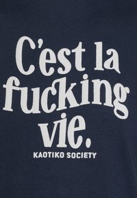 T-shirt bleu marine avec un grand texte blanc qui dit "C'est la fucking vie. KAOTIKO SOCIETY." Tissu doux, coupe décontractée, sans motifs.