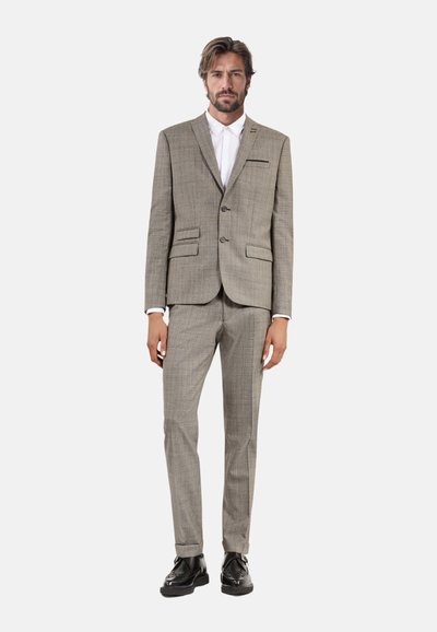 Braunes und beiges Karo-Anzug mit zweiknöpfigem Blazer, geraden Hosen. Weißes Hemd darunter, schwarze Schuhe, maßgeschneiderter Stil.