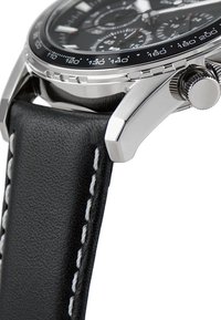 Bracelet de montre en cuir noir avec des coutures blanches. Boîtier en acier inoxydable argenté avec une finition texturée et une couronne proéminente. Cadran noir avec des fonctionnalités de chronographe.