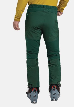 Grüne Skihosen aus weichem, dehnbarem Material, mit taillierter Passform, Reißverschlüssen an den Knöcheln und Taschen an den Seiten.