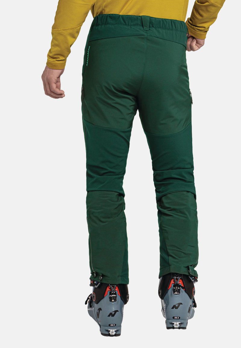 Grüne Skihosen aus weichem, dehnbarem Material, mit taillierter Passform, Reißverschlüssen an den Knöcheln und Taschen an den Seiten.