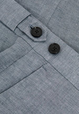 Grijze stof met een geweven textuur, twee zwarte knopen en een klep sluiting. Inclusief stikdetails en openingen voor zakken aan de zijkant.