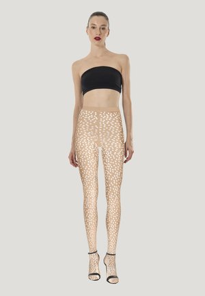 Doorzichtige, naakte legging met een wit polkadotpatroon. Draagt een zwarte strapless top en doorzichtige sandalen met hak. Soepele textuur.