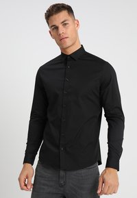 Schwarzes langärmliges Hemd aus leichtem Baumwollmaterial mit Button-Down-Kragen und einer durchgehenden Knopfleiste, das eine taillierte Passform aufweist und keine sichtbaren Muster hat.