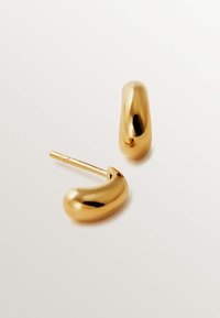 Pendientes de color dorado con una forma suave y curvada, parecida a un grano. Cuentan con un clip para un uso seguro. La superficie reflectante realza su diseño elegante.