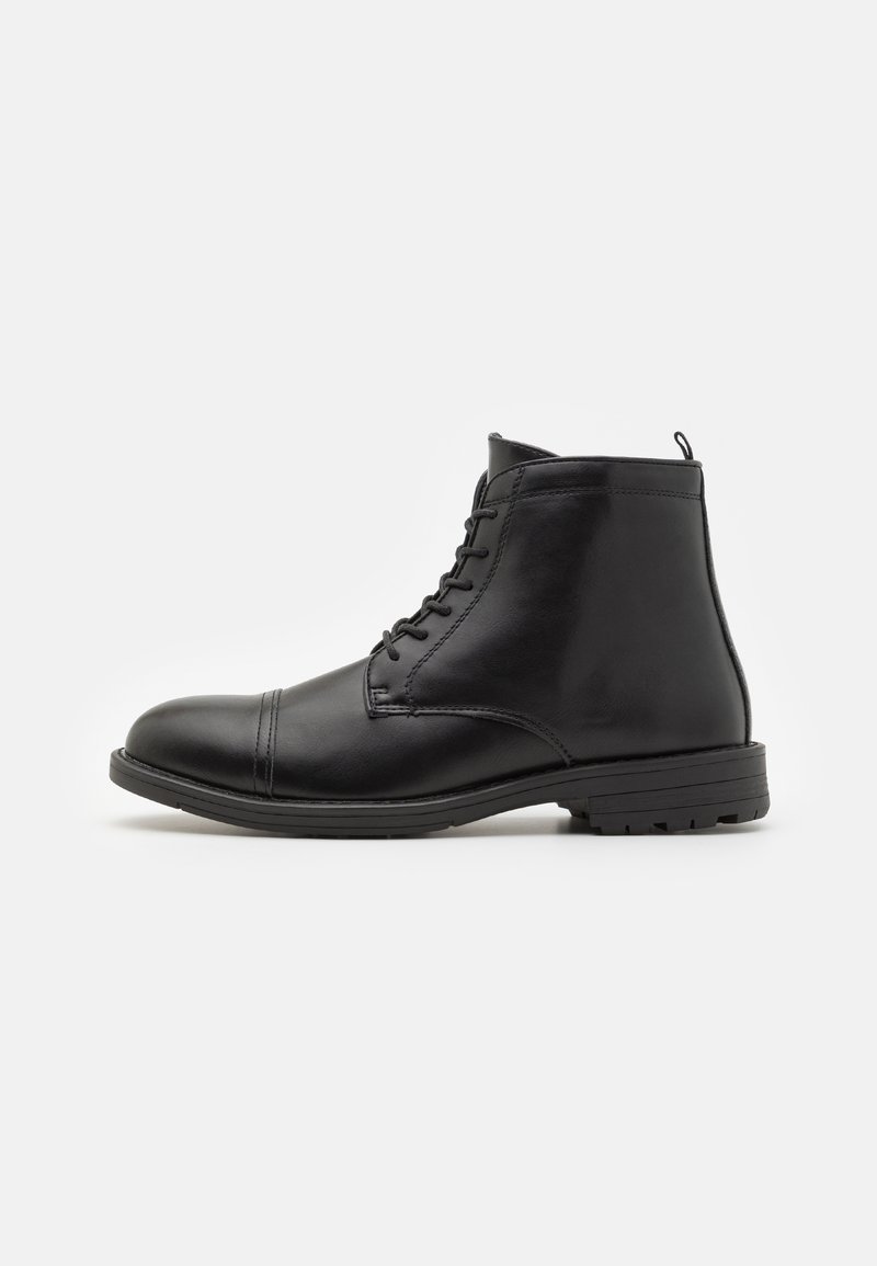 Bottine noire en cuir à lacets avec bout arrondi, petit talon et semelle texturée, vue de côté sur fond blanc.