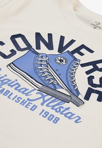 T-shirt en coton avec un graphique bleu de baskets montantes avec des accents blancs, du texte en gras "CONVERSE", et "Original Allstar Established 1908".
