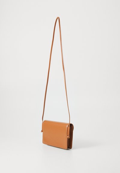 Geantă crossbody din piele de culoare tan, cu un finisaj neted, formă rectangulară și curea ajustabilă. Prezintă accente subtile sub formă de noduri la capete.