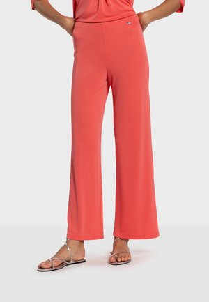 Pantaloni a gamba larga color corallo realizzati in tessuto morbido, con una comoda cintura in vita e un delicato dettaglio con logo. Abbinati a sandali argentati.