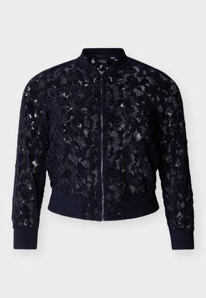 Blouson aviateur en dentelle noire avec motif floral, fermeture éclair frontale, col côtelé, poignets et taille, présenté sur fond blanc.