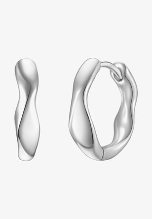 Pendientes de aro de plata con un diseño ondulado y escultórico. La superficie está pulida, reflejando la luz con contornos suaves y una textura sutil.
