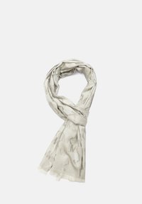 Sciarpa beige chiaro in un tessuto morbido e texture. Presenta un motivo sottile e bordi frangiati, drappeggiata in uno stile ad anello.