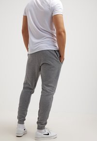 Gray cotton joggers with a slim fit, side pockets, ribbed cuffs, and a soft texture, paired with a white t-shirt and white sneakers.