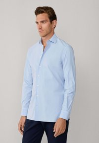 Lichtblauw katoenen overhemd met lange mouwen. Het heeft een button-down kraag, knopen aan de voorkant en een getailleerd ontwerp met knoopmanchetten.