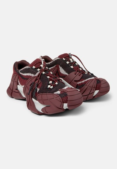 Baskets épaisses en tissu tricoté bordeaux, noir et blanc, semelles en caoutchouc épaisses et texturées, avec des lacets réglables à bouton-poussoir sur fond uni.