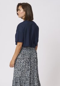 Top scurt din bumbac de culoare bleumarin, asortat cu o fustă lungă, cu un model care prezintă desene abstracte în bleumarin și alb, având talie elastică.