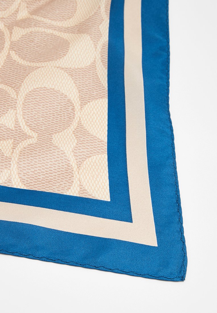 Foulard en soie avec un fond crème et un motif circulaire texturé, bordé de rayures bleu foncé et crème, avec un bord cousu.