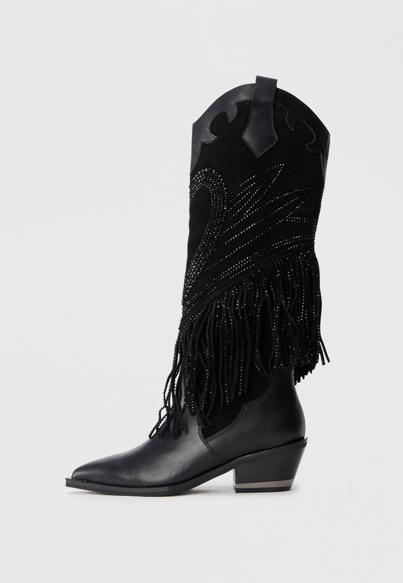 Stivale da cowboy nero con un alto gambale in suede, frange dettagliate e motivi di perline decorati. Punta affusolata e tacco angolare basso.