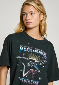 Black T-shirt with a graphic print featuring "PEPE JEANS LONDON" and starburst details. Short sleeves and a loose fit, cotton material.