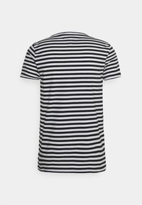 T-shirt às riscas em preto e branco, mangas curtas, gola redonda, material em algodão, corte regular, textura subtil, sem logótipos ou detalhes visíveis.