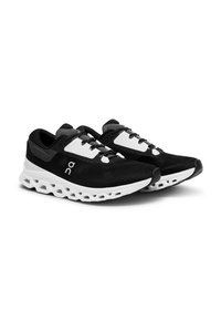 Zapatos deportivos negros con parte superior de malla, acentos blancos, cuello acolchado y diseño de suela con amortiguación visible. Cuenta con un sistema de lazado estándar.