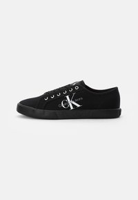 Černé nízké plátěné tenisky s černou gumovou podrážkou, černými tkaničkami a bílým logem "CK Calvin Klein Jeans" po straně.