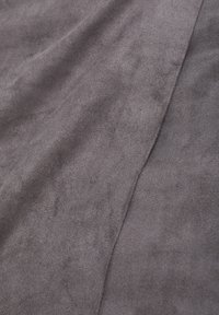 Grijze suede stof met een zachte, gestructureerde oppervlakte, met subtiele variaties in tint en een zichtbare naad voor extra detail.