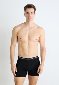 Sorte boksershorts med en BJOR̶N BORG livrem, laget av myk stoff, med en tettsittende passform og enkelt design, uten mønstre eller aksenter.