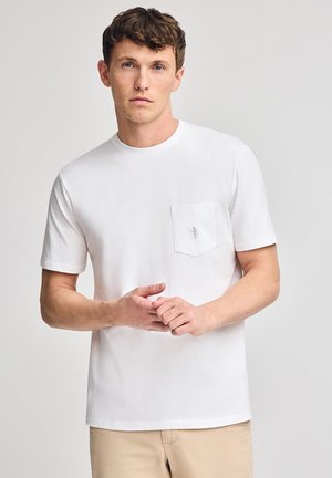 T-shirt en coton blanc avec un col rond et des manches courtes, doté d'une poche poitrine à gauche et d'un petit logo. Design simple et classique.