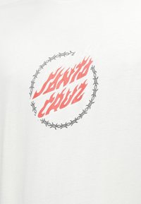 White cotton t-shirt featuring a central red and black graphic with the text "SANTA CRUZ" surrounded by a barbed wire design.