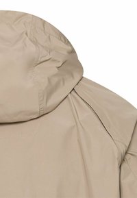 Beżowa kurtka z kapturem z widocznym przeszyciem, pokazująca górną część pleców i obszar ramion.