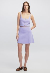 Lila cropped top met vierkante halslijn en drie gouden knopen, gecombineerd met een bijpassende flared mini rok. Textuurstof en geprinte schoenen.