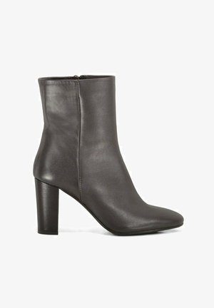 Bottine en cuir noir avec bout pointu, talon bloc haut et fermeture éclair latérale.