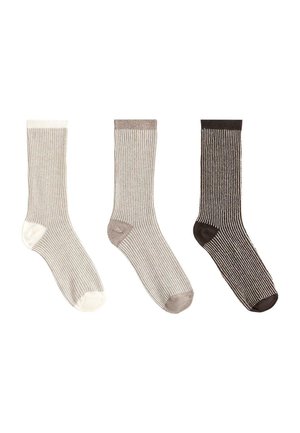 Trei șosete cu dungi, bej, cu accente albe, maro deschis și maro închis la călcâi și degete, aranjate unul lângă altul pe un fundal alb.