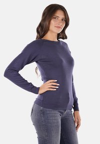 Maglione a maniche lunghe blu navy con scollo a girocollo, realizzato in materiale morbido, caratterizzato da polsini e orlo a coste, texture liscia e design aderente.