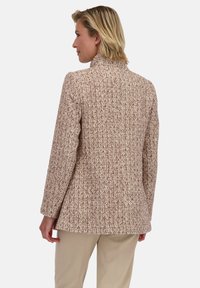 Textuur, geweven jas in lichte beige en browntinten; heeft een kraag en lange mouwen, met een ontspannen pasvorm en een getailleerde snit.