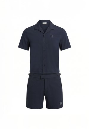 Chemise bleu marine à manches courtes avec boutons et short assorti avec ceinture et petit logo sur la poitrine et le short.