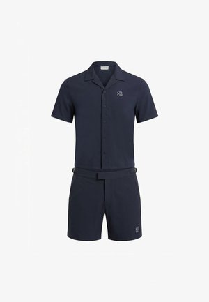Chemise bleu marine à manches courtes avec boutons et short assorti avec ceinture et petit logo sur la poitrine et le short.