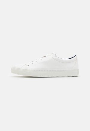 Sneaker in pelle bianca con punta tonda, suola piatta in gomma e design con lacci. Presenta cuciture minime e un interno a contrasto in colore navy.