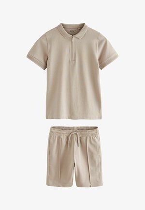 Beige poloshirt met een korte rits en kraag, gecombineerd met bijpassende shorts met een elastische tailleband en zijzakken.