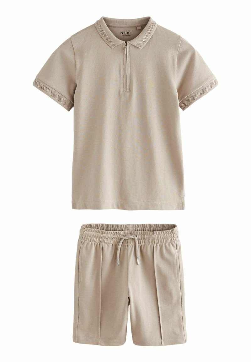 Beige Poloshirt mit kurzem Reißverschluss und Kragen, kombiniert mit passenden Shorts mit elastischem Bund und Seitentaschen.