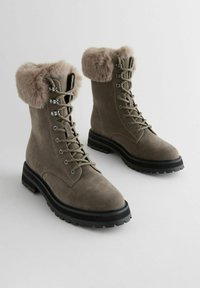 Graue Wildleder-Schnürstiefel mit einem gemütlichen Kunstfellkragen, dicker schwarzer Gummisohle und silberfarbenen Hardware-Akzenten an den Schnürsenkeln.