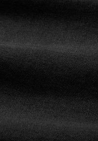 Crni materijal s glatkom teksturom, s uzorkom tkanja riblje kosti. Tkanina djeluje lagano s mekim naborima.