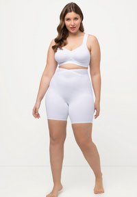 Sostenitore bianco senza cuciture e pantaloni corti a vita alta, con una texture liscia e un design incrociato in vida. Nessun elemento di fissaggio visibile.