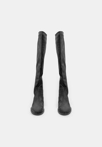 Botas de ante negras por encima de la rodilla con suela plana, que presentan un diseño aerodinámico y una textura suave. Sin herrajes visibles ni adornos.