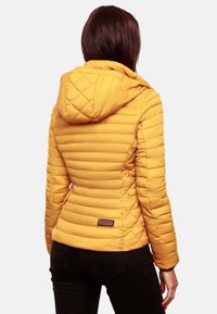 Yellow padded jacket with a hood, featuring quilted lines and a brand label near the hem. Smooth texture and fitted design.