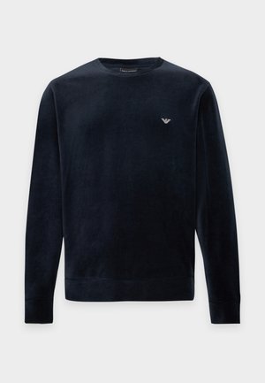 Sweat-shirt bleu marine foncé à manches longues et col rond, avec des poignets et un bas côtelés ainsi qu’un petit logo blanc sur la poitrine.