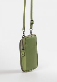 Green leather crossbody bag with a rectangular shape, zip closure, and adjustable strap. Features smooth texture and contrasting stitching.